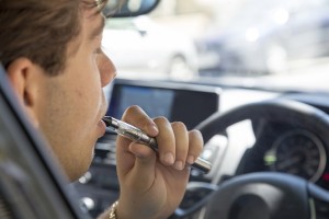 Mann raucht im Auto E-Zigarette